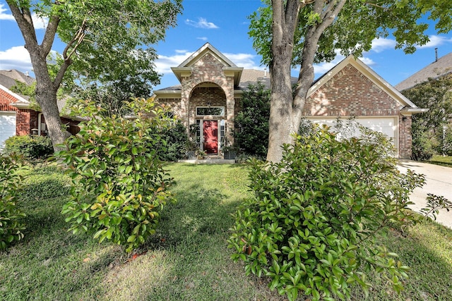 10110 Andre Dr, Irving, TX 75063 - obstructed view of property featuring an attached garage, concrete driveway, brick siding, and a front lawn