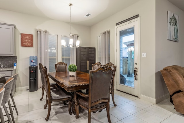 dining room with an inviting chandelier, light tile patterned floors, visible vents, and baseboards