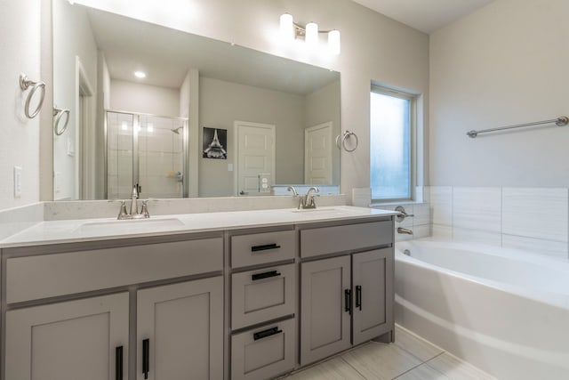 bathroom with a stall shower, a garden tub, double vanity, and a sink