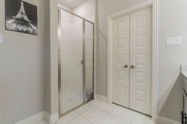 full bath with tile patterned floors, vanity, baseboards, and a shower stall