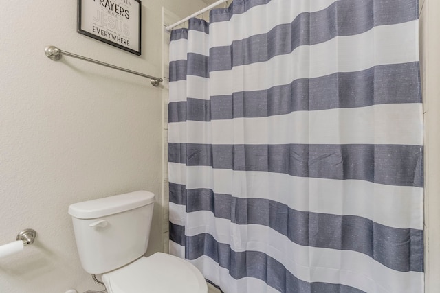bathroom with toilet and a shower with shower curtain