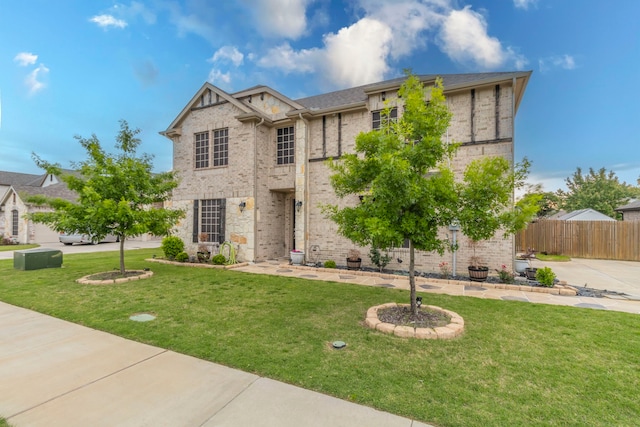 view of front of home featuring brick siding, fence, and a front yard