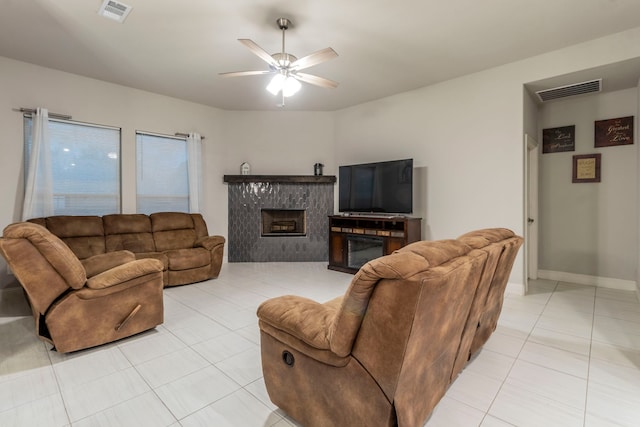 living room with a ceiling fan, a glass covered fireplace, light tile patterned floors, and visible vents