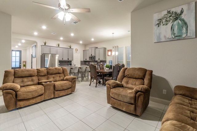 living area featuring light tile patterned floors, visible vents, ceiling fan with notable chandelier, and recessed lighting