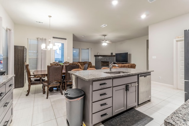 kitchen featuring a sink, gray cabinets, stainless steel dishwasher, light stone countertops, and visible vents