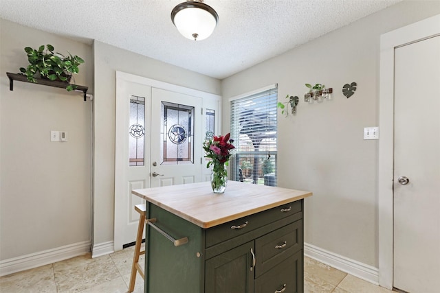 7340 Blackthorn Dr, Fort Worth, TX 76137 - kitchen featuring butcher block counters, baseboards, a textured ceiling, and a center island