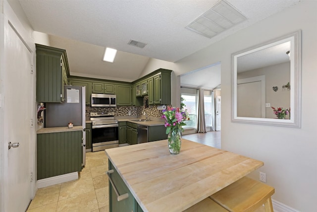 7340 Blackthorn Dr, Fort Worth, TX 76137 - kitchen featuring green cabinets, appliances with stainless steel finishes, light countertops, decorative backsplash, and vaulted ceiling