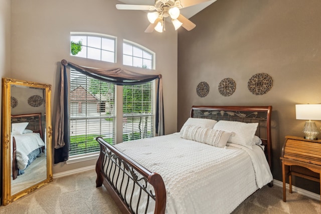 carpeted bedroom featuring baseboards, ceiling fan, and a high ceiling