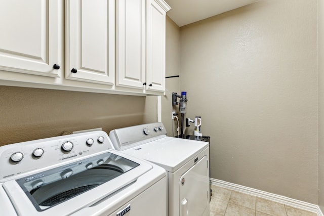 laundry room featuring baseboards, separate washer and dryer, light tile patterned floors, and cabinet space