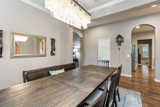 dining room featuring ornamental molding, arched walkways, baseboards, and wood finished floors