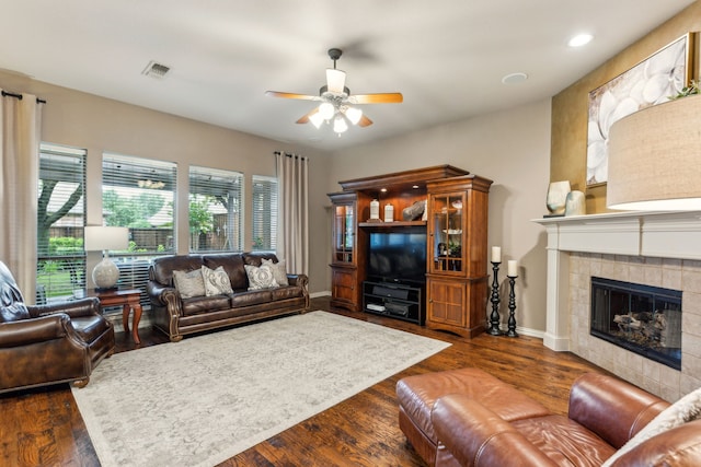 living area featuring baseboards, ceiling fan, visible vents, a tile fireplace, and dark wood-style floors