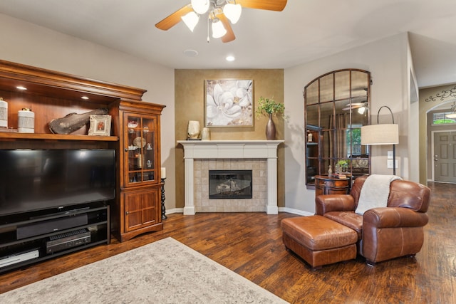 living room with baseboards, a tile fireplace, ceiling fan, and wood finished floors