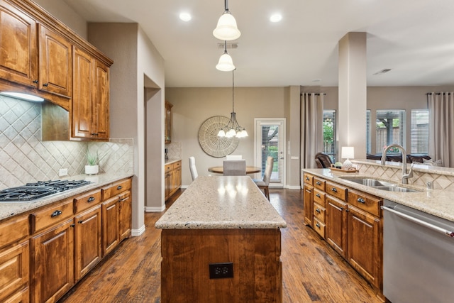 kitchen featuring light stone countertops, a sink, a kitchen island, tasteful backsplash, and appliances with stainless steel finishes