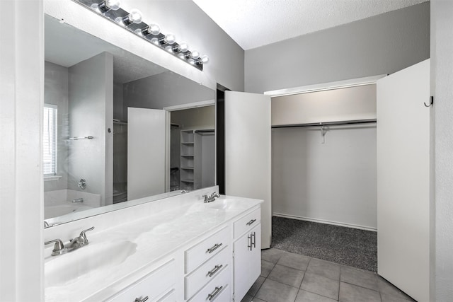full bathroom featuring tile patterned floors, a sink, and a walk in closet