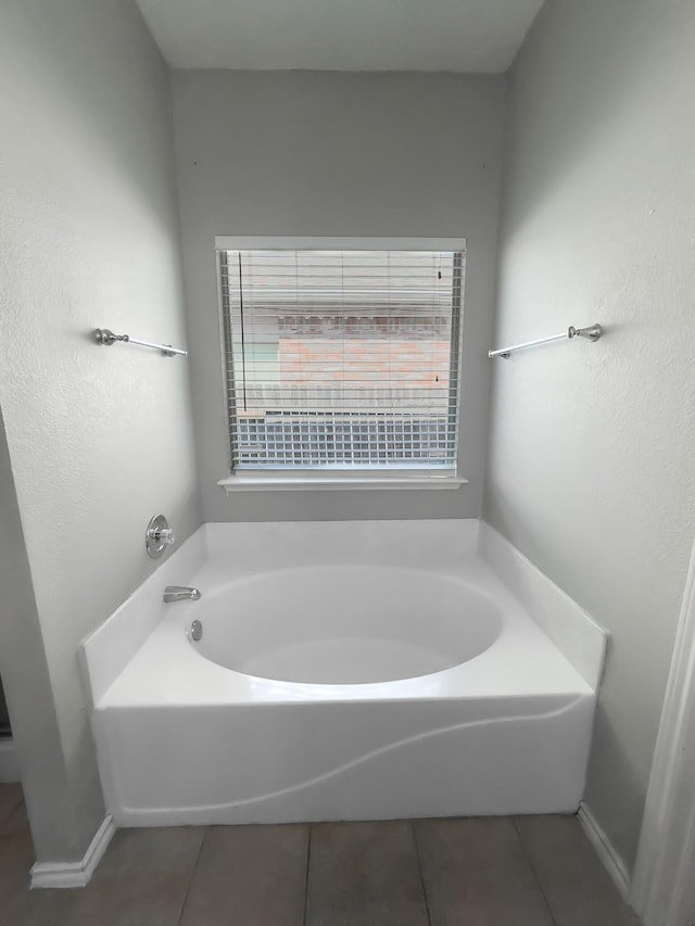 bathroom with a garden tub, plenty of natural light, and tile patterned flooring