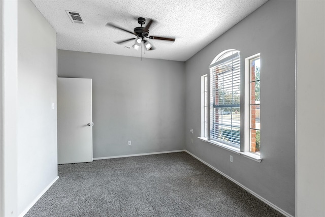 carpeted empty room with baseboards, visible vents, ceiling fan, and a textured ceiling