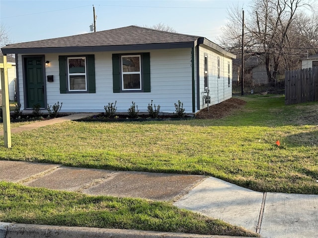 view of front of house with a front lawn, a shingled roof, and fence