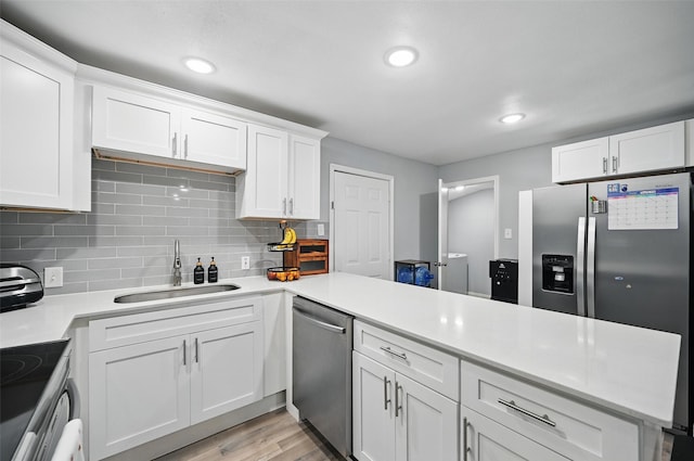 11519 Desdemona Dr, Dallas, TX 75228 - kitchen featuring appliances with stainless steel finishes, a sink, a peninsula, tasteful backsplash, and light countertops