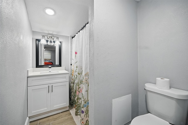 11519 Desdemona Dr, Dallas, TX 75228 - full bath featuring wood finished floors, toilet, vanity, a textured wall, and curtained shower