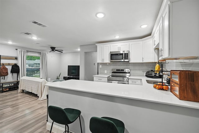 11519 Desdemona Dr, Dallas, TX 75228 - kitchen featuring appliances with stainless steel finishes, a peninsula, backsplash, light countertops, and white cabinetry