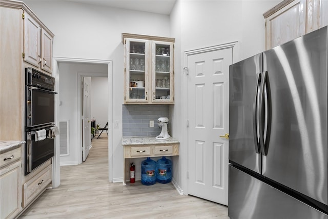 3811 Maywood Dr, Carrollton, TX 75007 - kitchen featuring freestanding refrigerator, light wood-style floors, glass insert cabinets, backsplash, and light stone countertops