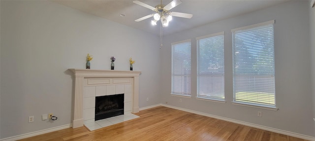 unfurnished living room with a fireplace, ceiling fan, baseboards, and light wood-type flooring