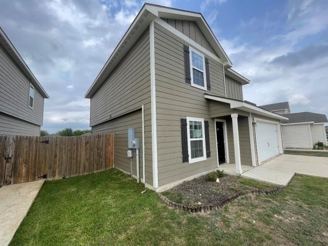 11757 Davalos Ln, San Antonio, TX 78252 - view of side of home featuring fence, a yard, concrete driveway, a garage, and board and batten siding
