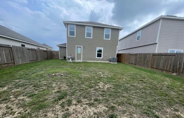 11757 Davalos Ln, San Antonio, TX 78252 - back of house featuring cooling unit, a lawn, and a fenced backyard