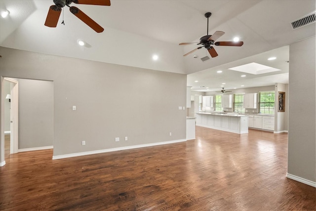 unfurnished living room featuring a skylight, visible vents, ceiling fan, baseboards, and light wood-style floors