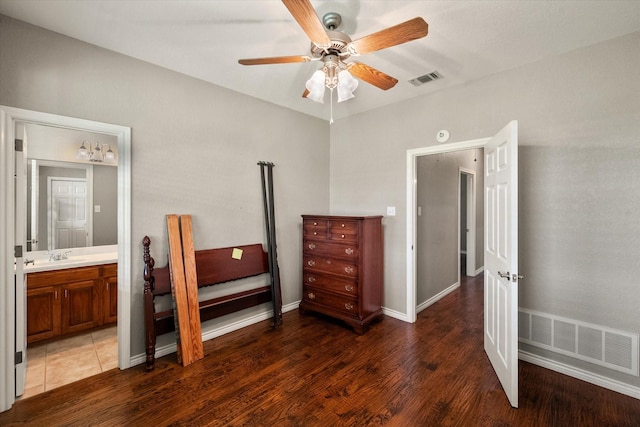 bedroom featuring ensuite bathroom, baseboards, visible vents, and wood finished floors
