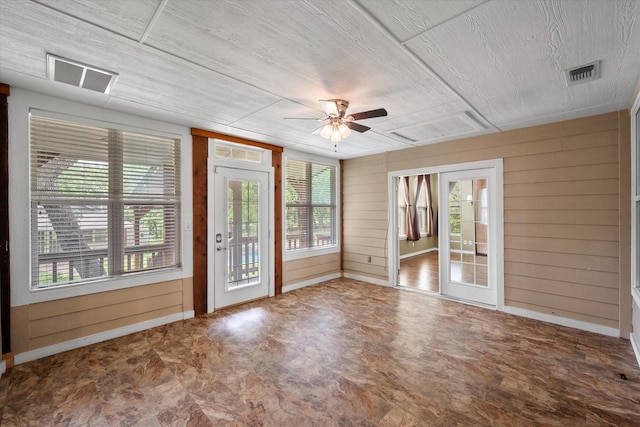 interior space with wooden walls, a wealth of natural light, and visible vents