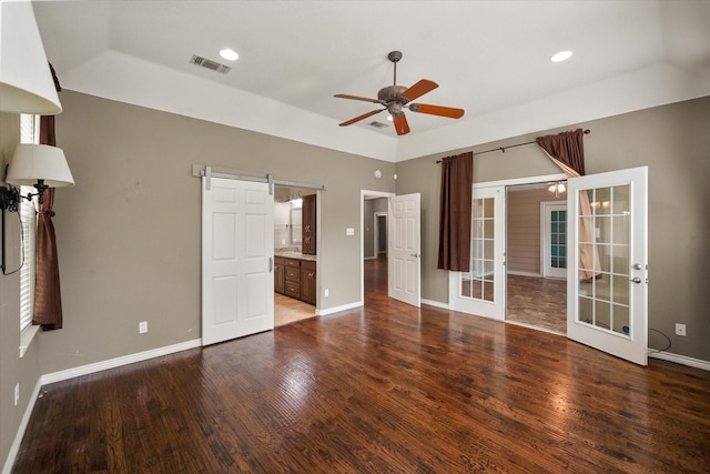 unfurnished bedroom with wood finished floors, french doors, visible vents, a barn door, and baseboards