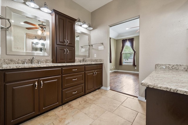 bathroom with a ceiling fan, baseboards, double vanity, and a sink