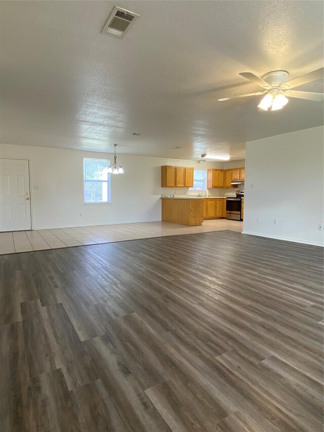 4406 Bobbie Ann Dr, Granbury, TX 76049 - unfurnished living room with visible vents, ceiling fan with notable chandelier, a textured ceiling, and wood finished floors