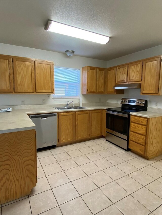 4406 Bobbie Ann Dr, Granbury, TX 76049 - kitchen featuring under cabinet range hood, light tile patterned flooring, a sink, light countertops, and appliances with stainless steel finishes