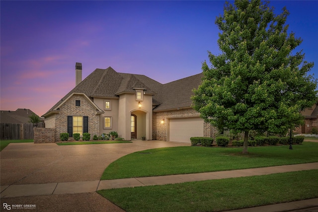 french country home with fence, a chimney, a lawn, brick siding, and driveway