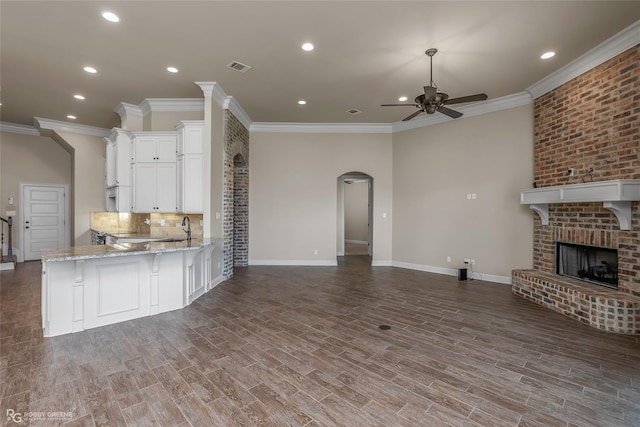 kitchen with a sink, crown molding, white cabinetry, open floor plan, and a ceiling fan