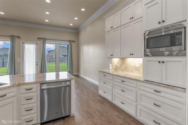 kitchen featuring baseboards, ornamental molding, backsplash, stainless steel appliances, and white cabinets