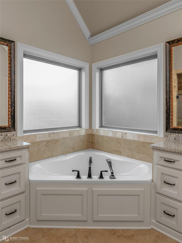 bathroom with ornamental molding, a garden tub, vanity, and vaulted ceiling