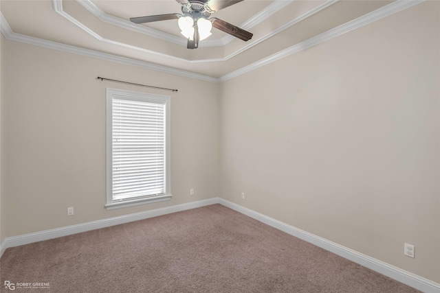 carpeted spare room featuring baseboards, crown molding, a tray ceiling, and ceiling fan