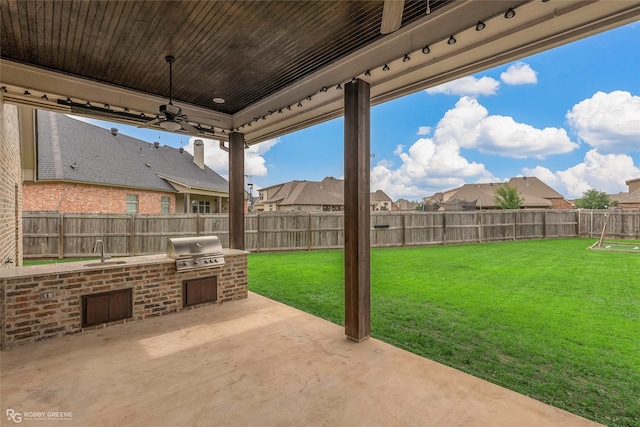 view of patio / terrace featuring area for grilling, exterior kitchen, a sink, a residential view, and a fenced backyard
