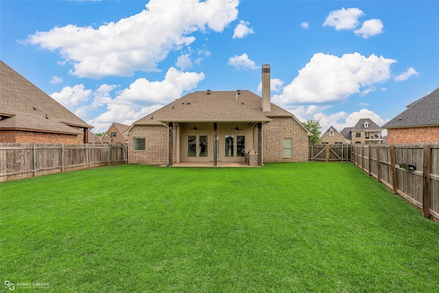 rear view of property with a patio, a chimney, a fenced backyard, ceiling fan, and brick siding