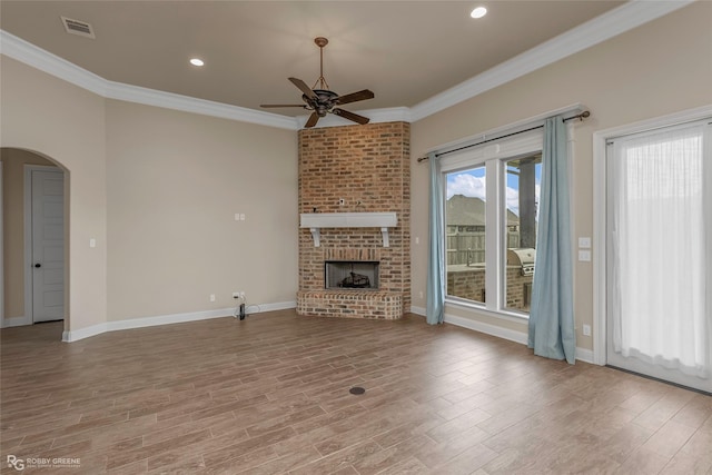 unfurnished living room featuring visible vents, ceiling fan, crown molding, wood finished floors, and arched walkways