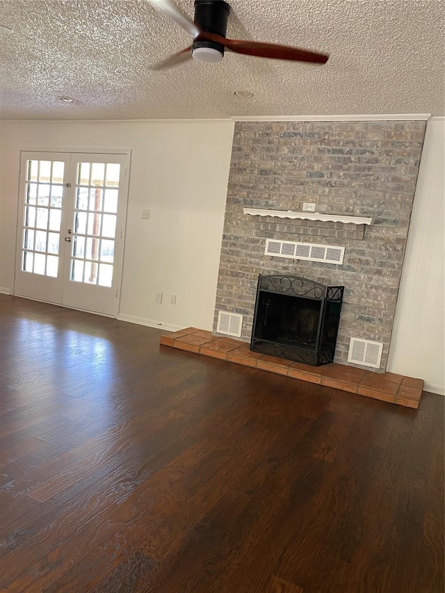 unfurnished living room with a fireplace with raised hearth, visible vents, a textured ceiling, and wood finished floors
