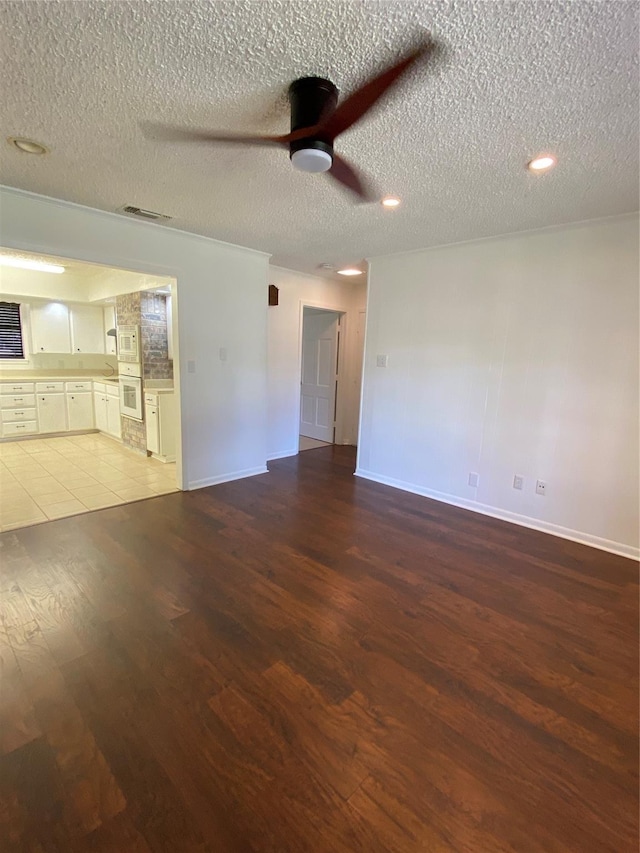 unfurnished living room featuring a textured ceiling, a ceiling fan, visible vents, and wood finished floors
