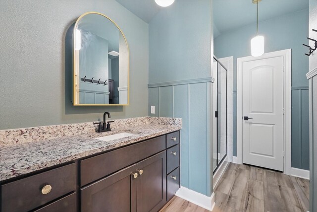 7616 Duck Bay Rd, Fort Worth, TX 76120 - bathroom featuring wood finished floors, a shower stall, vanity, and a wainscoted wall