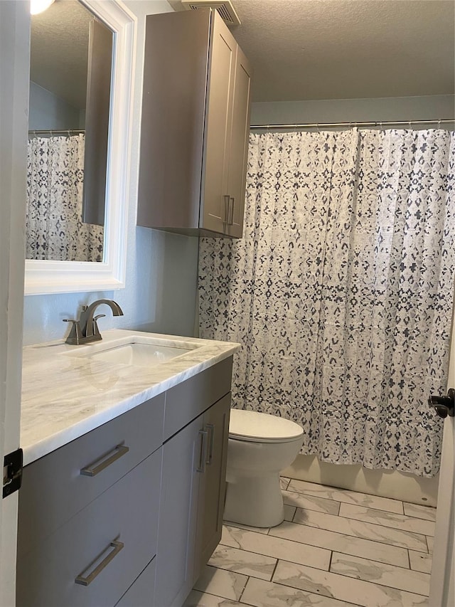 bathroom featuring toilet, marble finish floor, vanity, a textured ceiling, and a shower with shower curtain