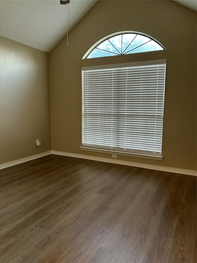 empty room featuring dark wood finished floors, vaulted ceiling, and baseboards