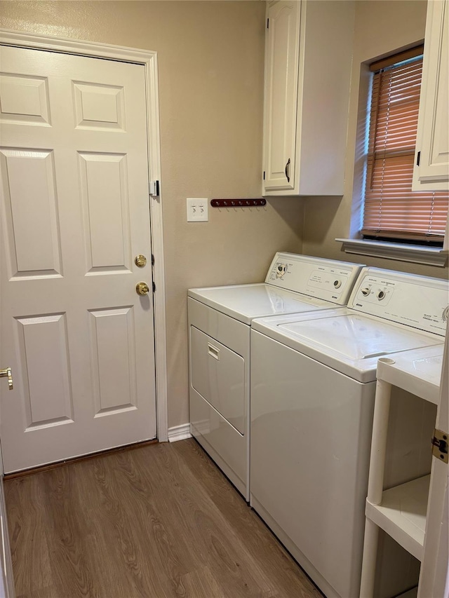 laundry room featuring cabinet space, washer and clothes dryer, and dark wood finished floors