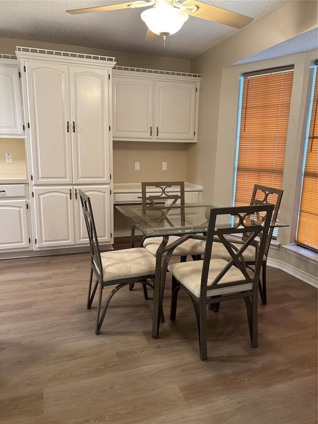 dining area with a textured ceiling, baseboards, light wood-style flooring, and a ceiling fan